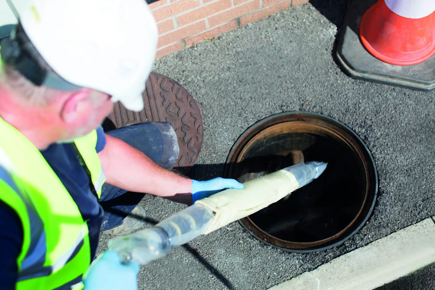 Drainage engineer inserting a patch repair liner into a manhole