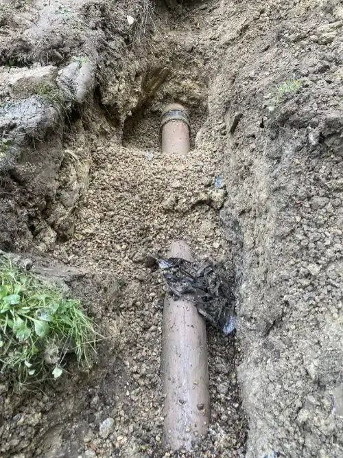 Mini excavator carrying out groundwork for a drain repair